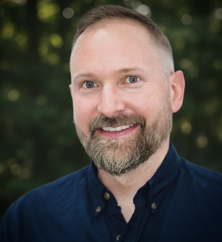 Headshot of Keith in front of green background.
